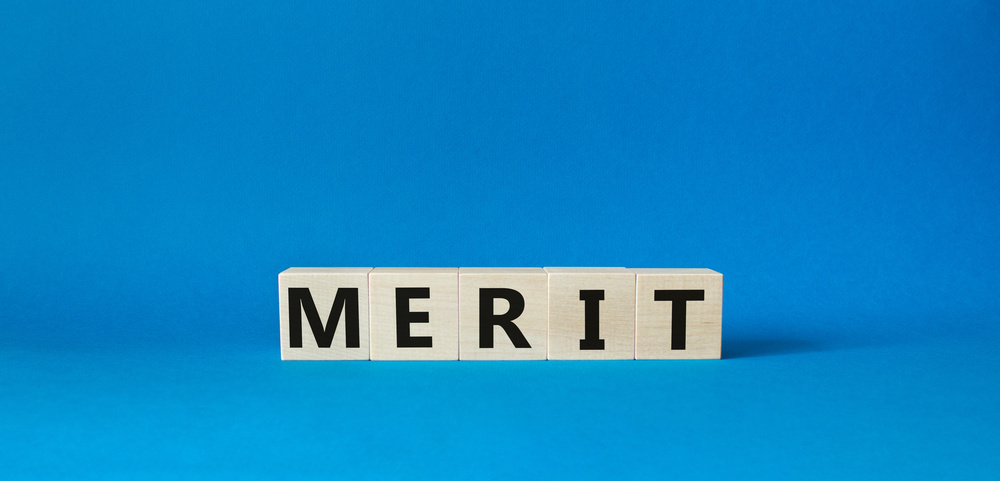 Merit symbol. Concept word Merit on wooden cubes. Beautiful blue background. Business and Merit concept. Copy space.