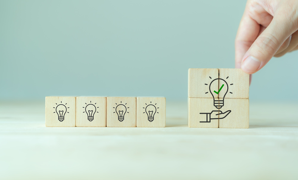 Suggestion and consulting concept. New idea, solution. Putting wooden cubes with light bulb on hand icon on beuatiful grey background and copy space. Business review, strategy suggestion for busines