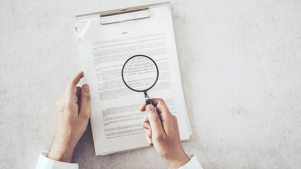 Man hands looking document with magnifying glass